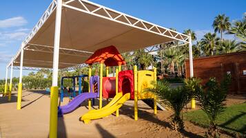A playground with slides and climbing structures under a white canopy.