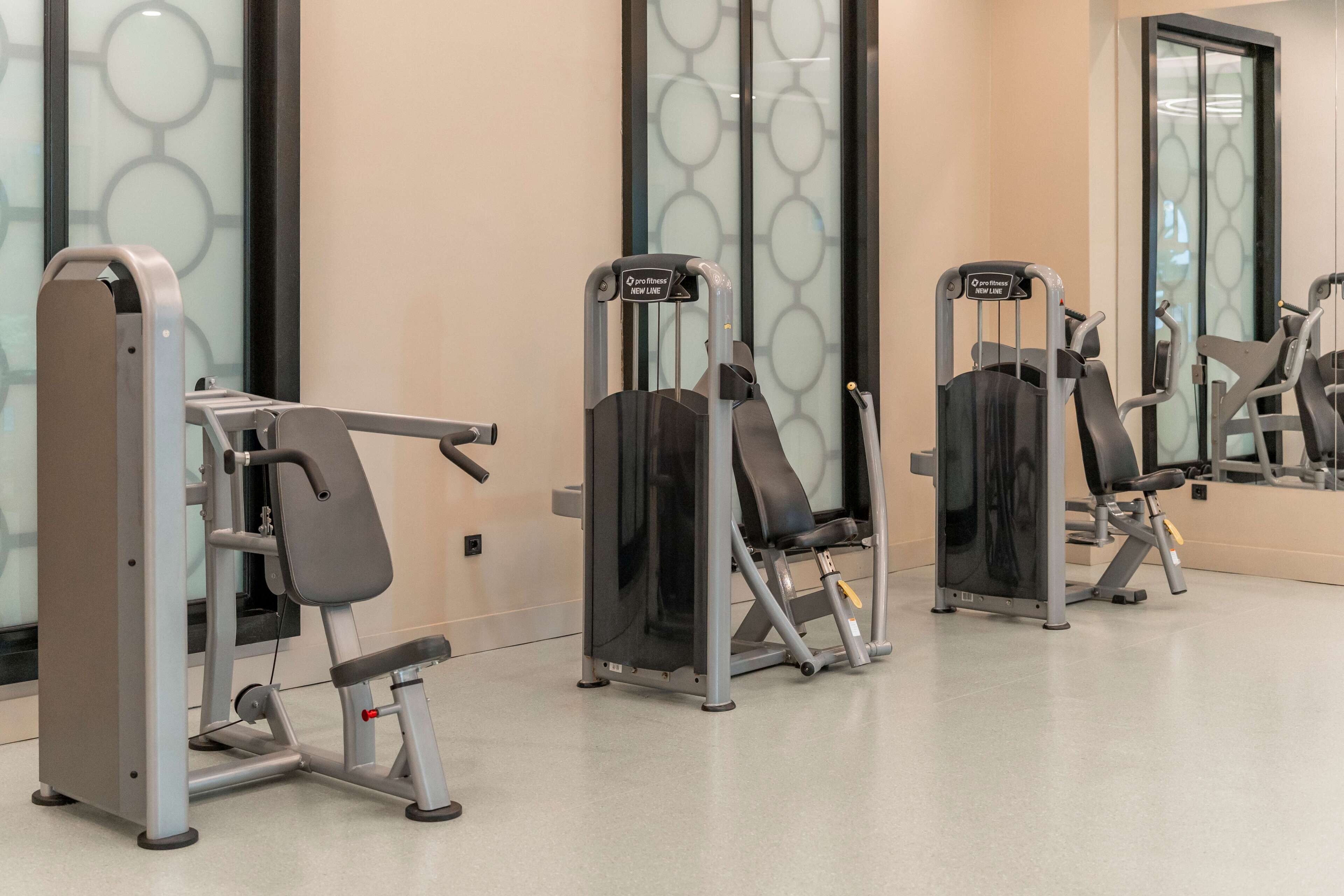 Ein Fitnessraum mit Trainingsgeräten, einem Spiegel und einer Wand mit kreisförmigen Mustern.