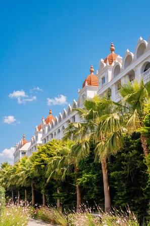 A large, multi-story building with a symmetrical facade, featuring a series of arches and domed roofs. - Oz Hotels Side Premium (Manavgat)