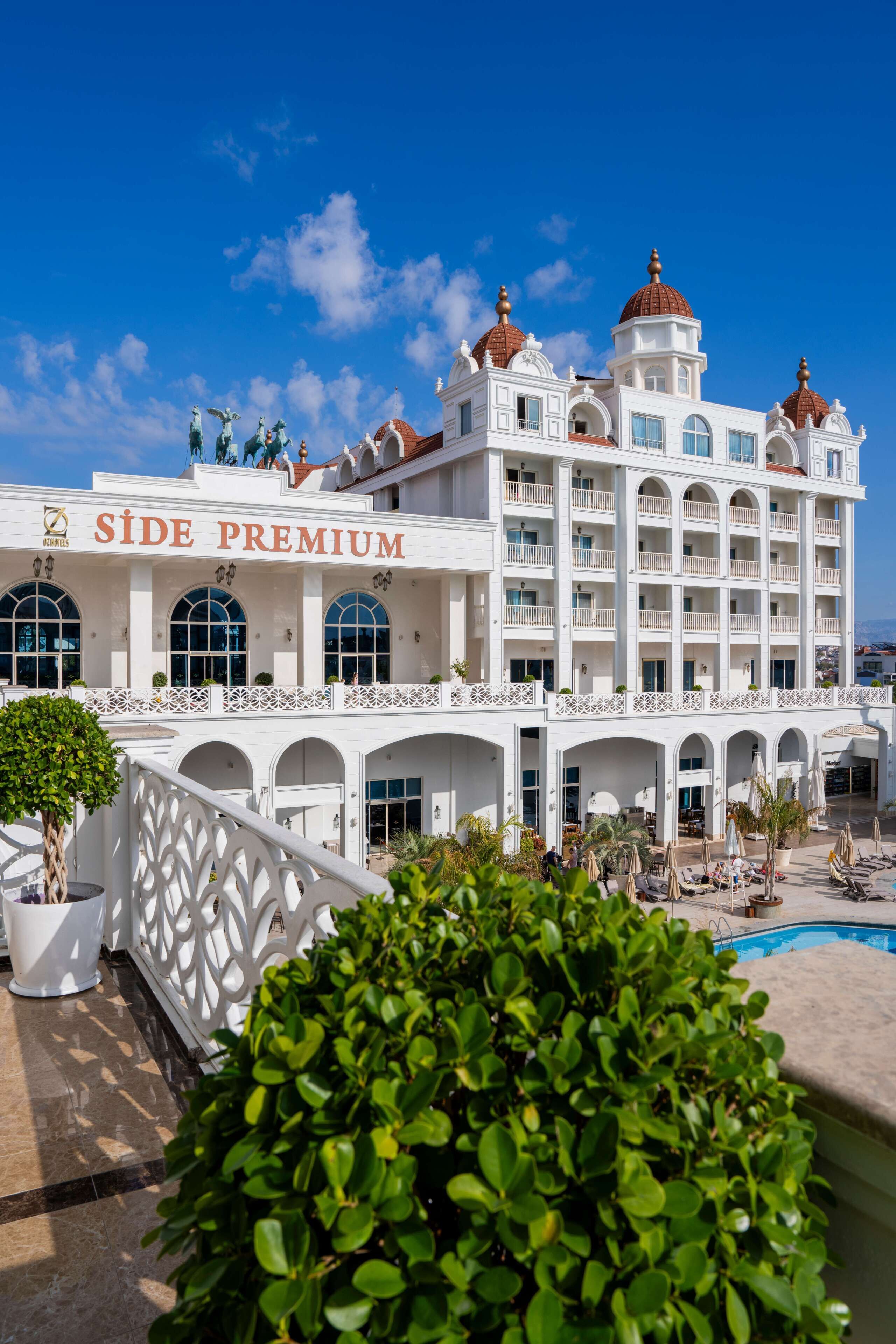 A hotel with a prominent 'SIDE PREMIUM' sign, multiple balconies, and a pool area.