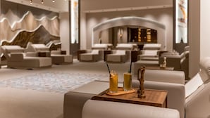 A modern lounge area with sofas, a wooden table with drinks, and a decorative wall. - Oz Hotels Side Premium (Manavgat)