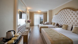 A hotel room with a large bed, a smaller bed, a desk with a kettle, and a mirror. - Oz Hotels Side Premium (Manavgat)