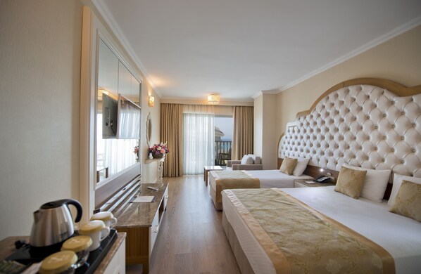 A hotel room with a large bed, a smaller bed, a desk with a kettle, and a mirror. - Oz Hotels Side Premium (Manavgat)
