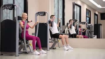 A fitness center with exercise machines and mirrors.