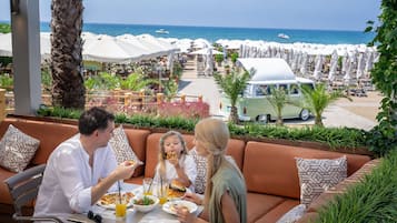 A dining area with a view of the beach and umbrellas.