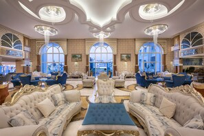 A luxurious lobby with ornate chandeliers, elegant seating, and large windows offering a view. - Oz Hotels Side Premium (Manavgat)