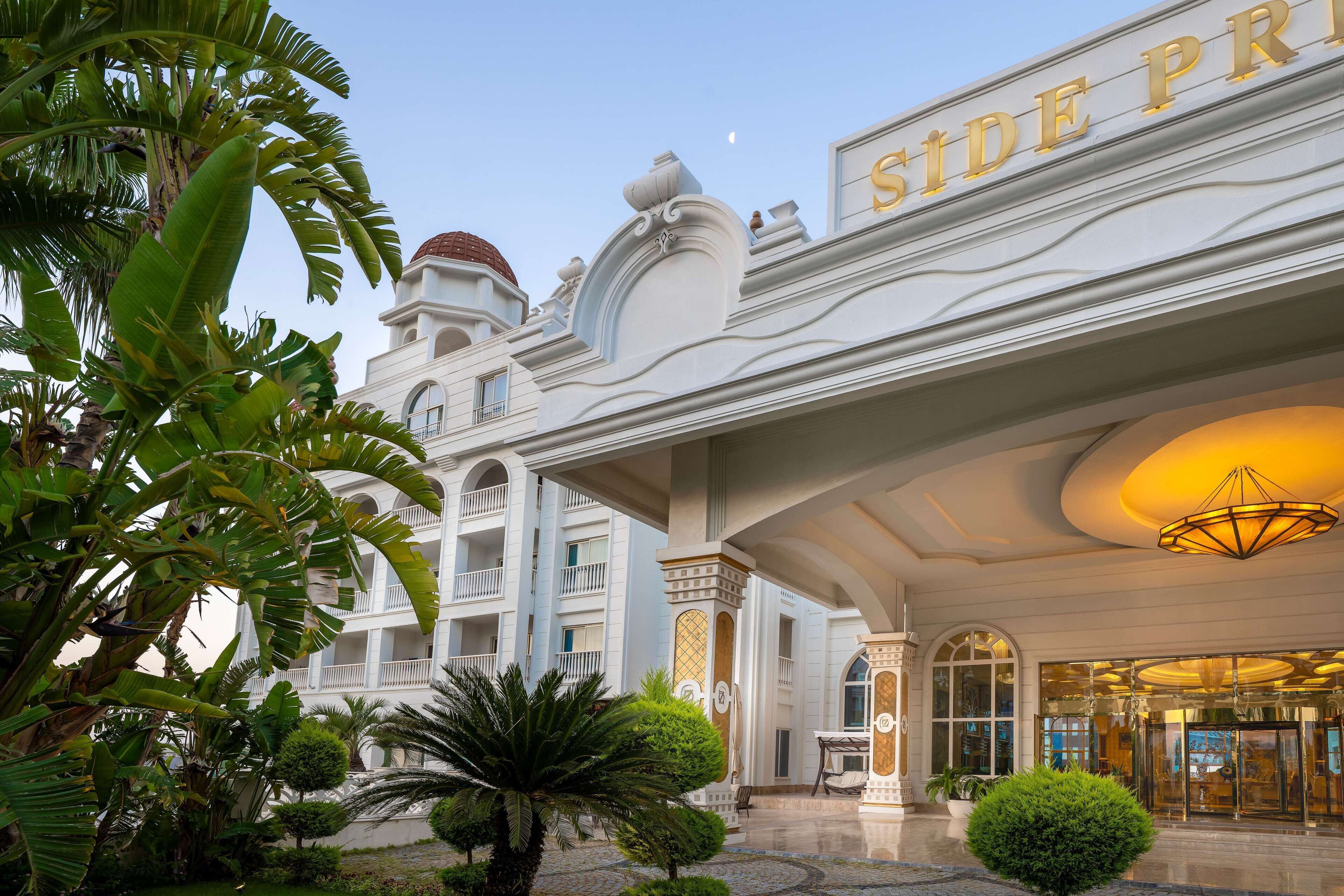 A hotel entrance with a grand facade, a dome structure, and a well-maintained garden.