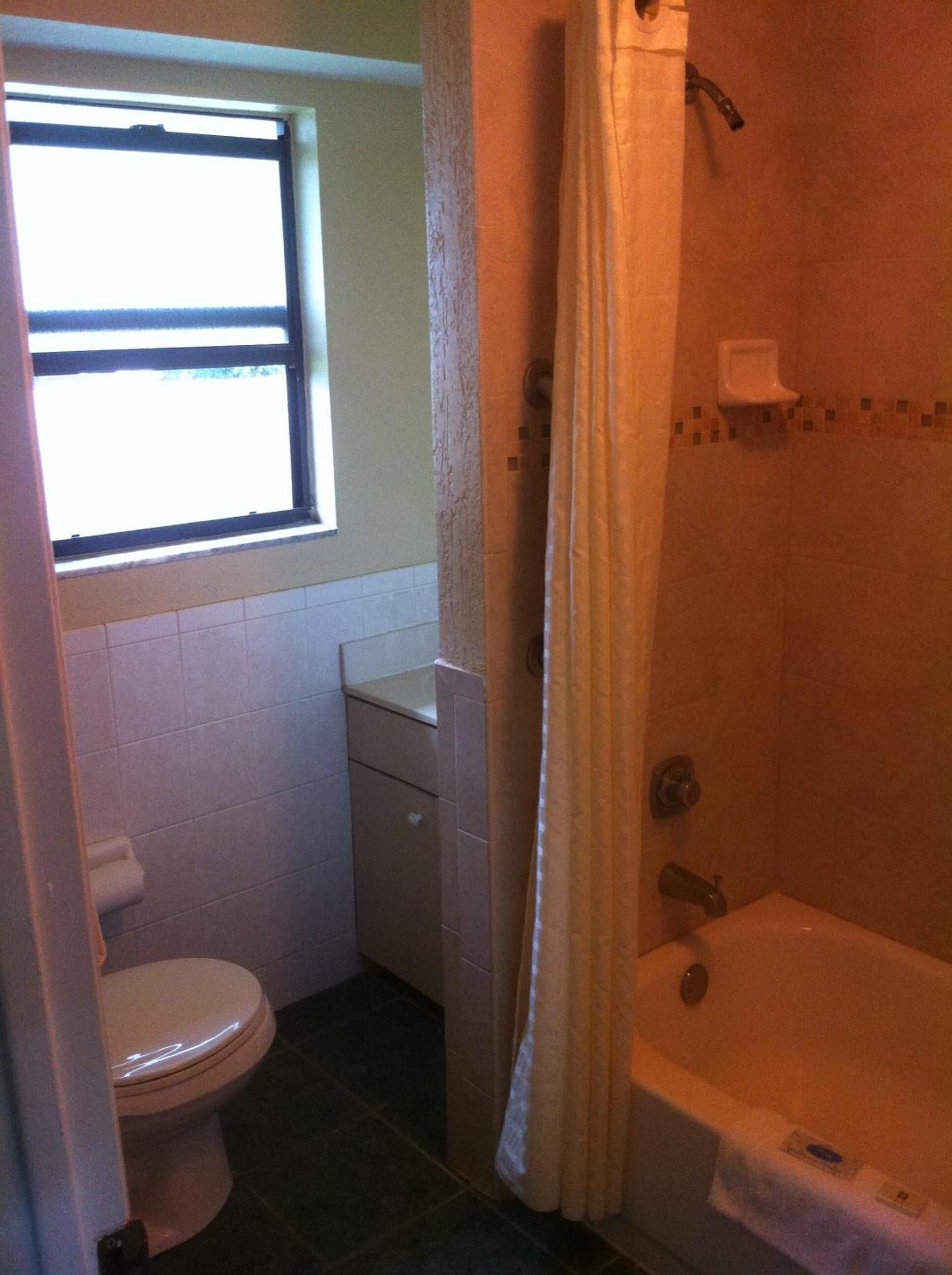 Une petite salle de bain avec des toilettes, une fenêtre et une baignoire.