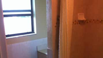 Une petite salle de bain avec des toilettes, une fenêtre et une baignoire.