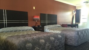 A hotel room with two beds, a nightstand, a lamp, a desk, and a chair. - Orange City Motel (Orange City)