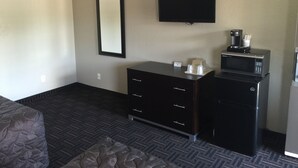 A hotel room with a bed, a dresser, a flat-screen TV, a microwave, and a coffee maker. - Orange City Motel (Orange City)