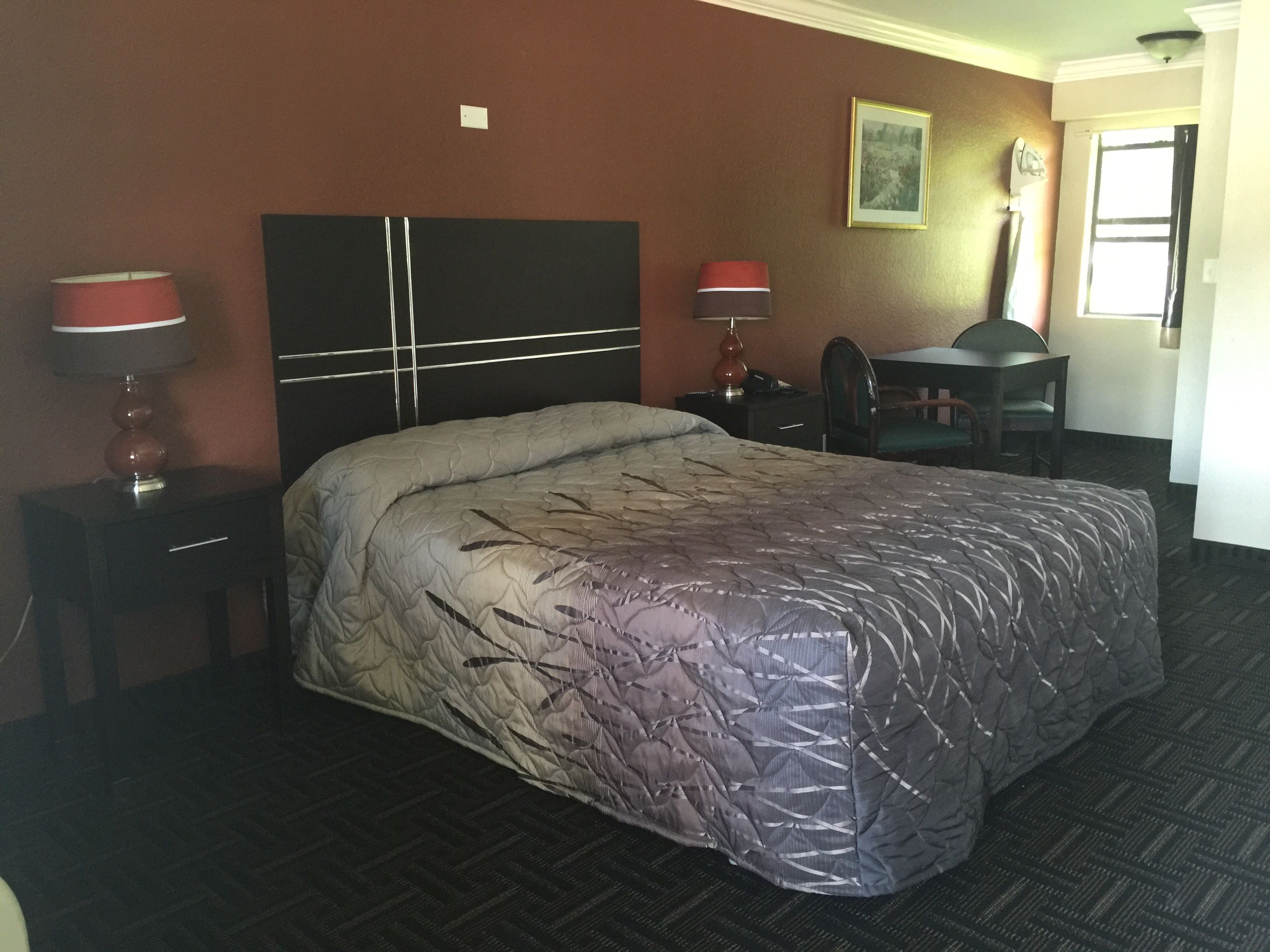 Una habitación de hotel con una cama grande, dos mesitas de noche con lámparas, un escritorio y una silla.
