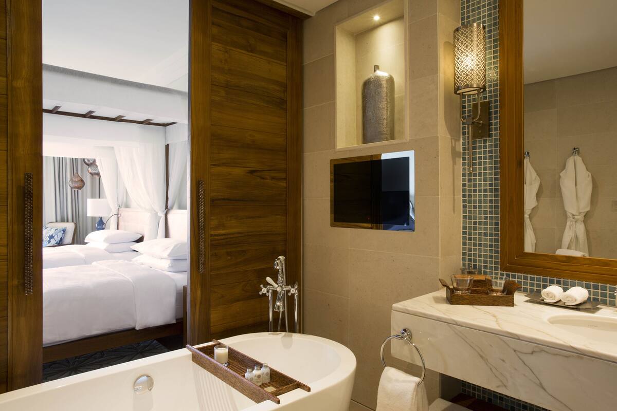 A modern bathroom with a bathtub, a vanity with a mirror, and a shower area.