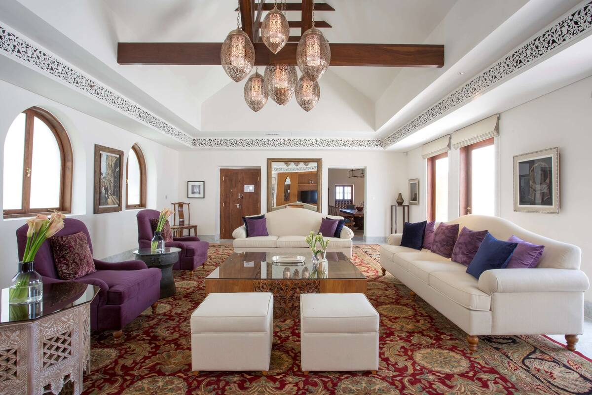 A spacious living room with a large sofa, two armchairs, a coffee table, and a patterned rug.