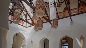 Een interieur met hoge plafonds, gewelfde deuropeningen en hangende kroonluchters.