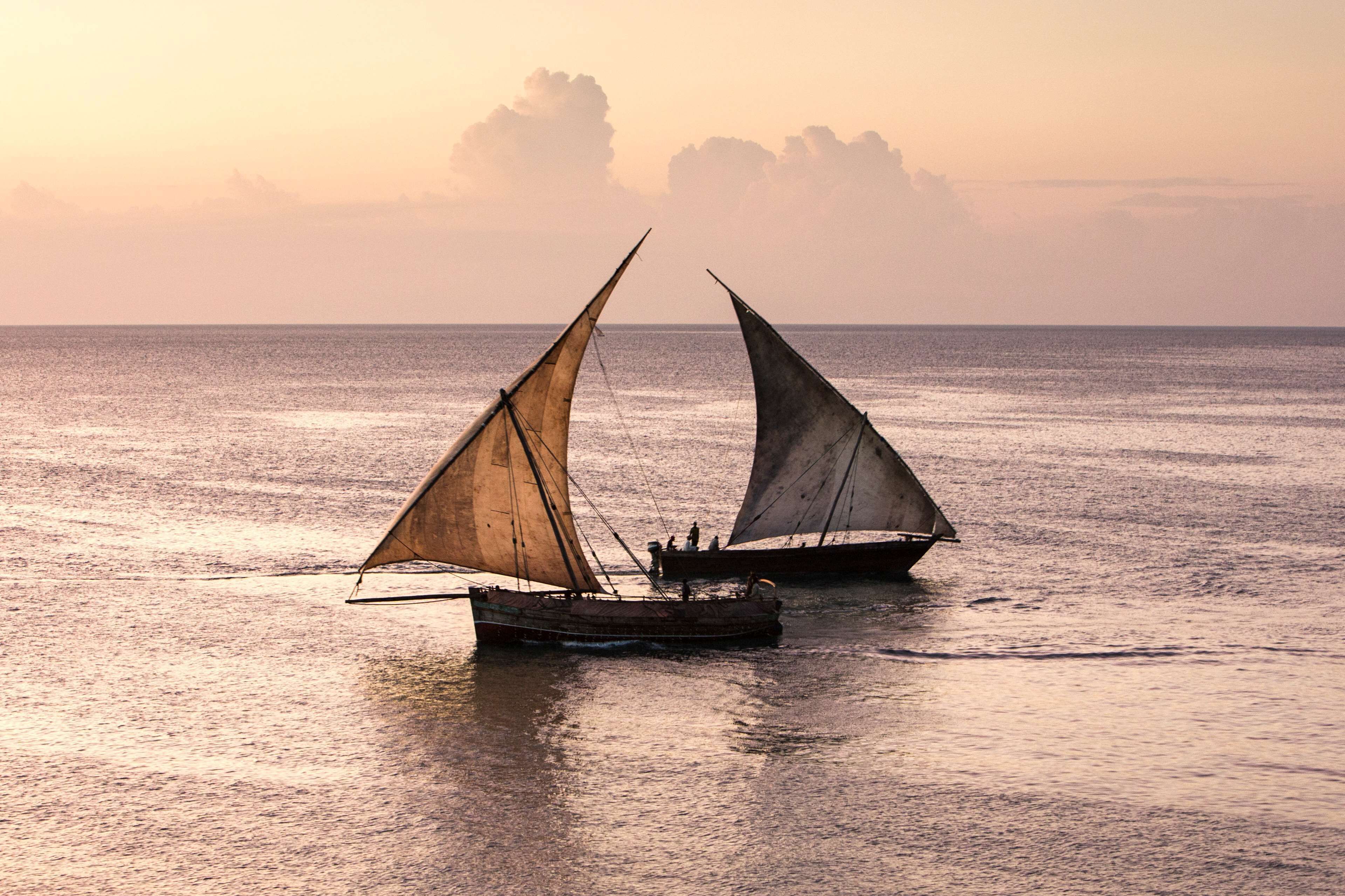 Deux voiliers traditionnels sur des eaux calmes, au coucher du soleil.