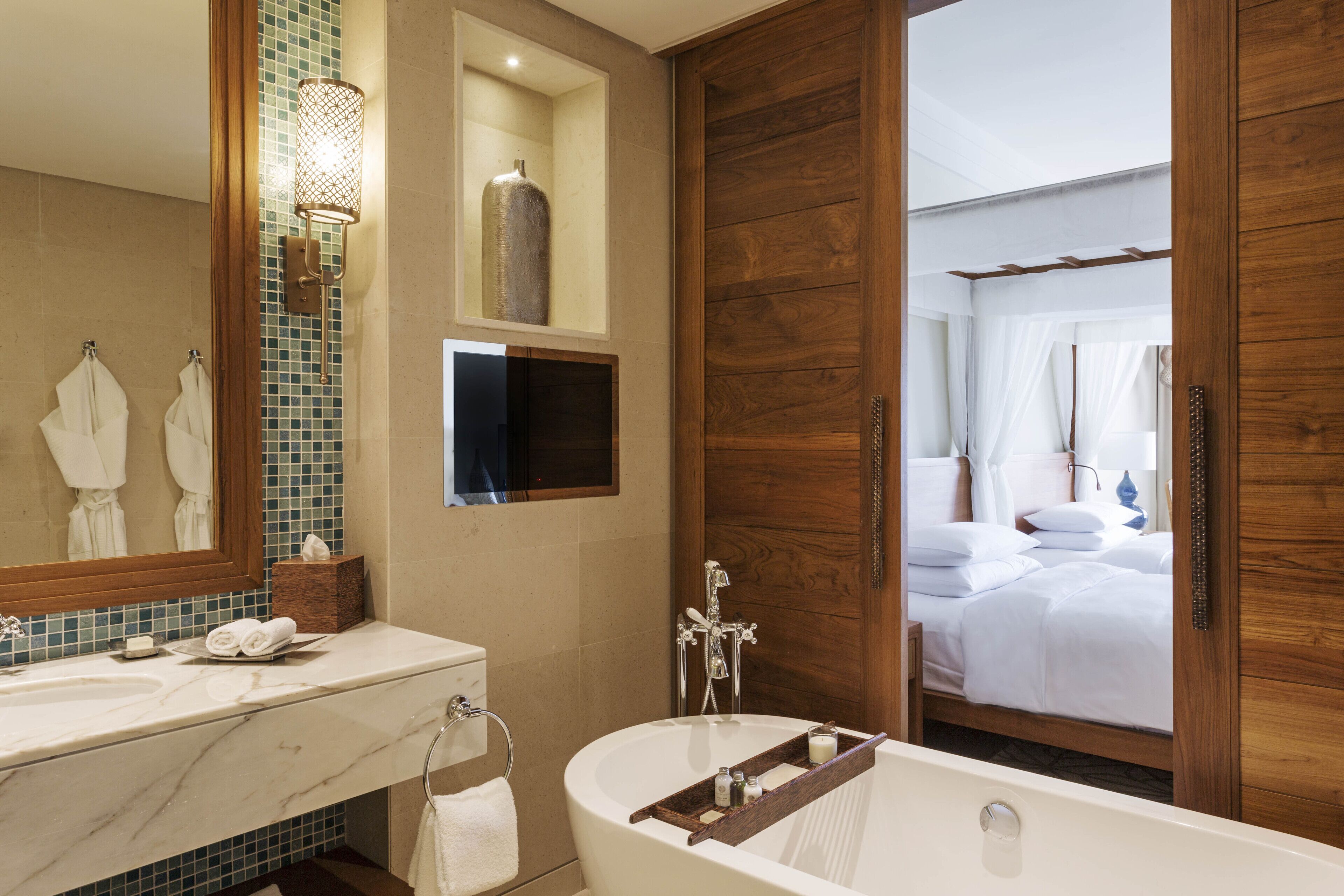 A bathroom with a marble sink, a freestanding bathtub, a large mirror, and wooden paneling.