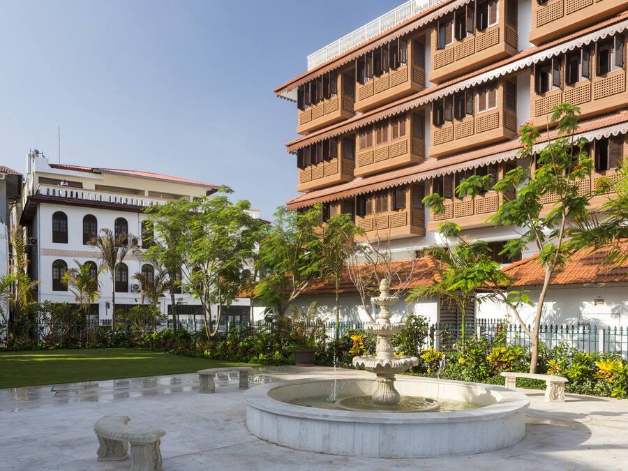 A courtyard with a fountain, surrounded by a white building with balconies and a red-tiled roof.