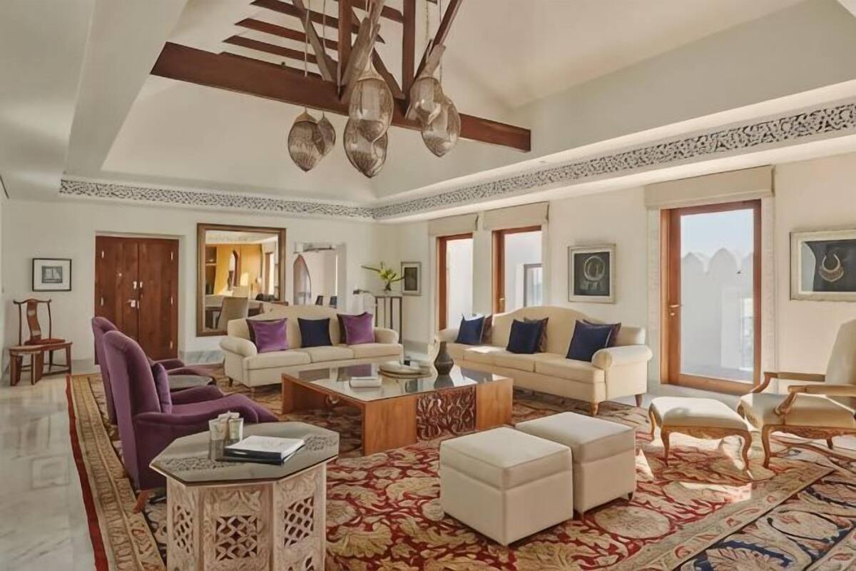A spacious living room with a high ceiling, a large sofa set, a coffee table, and a patterned rug.