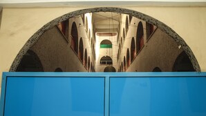 Blick durch ein großes, rundes Fenster mit einer blauen Struktur im Vordergrund.
