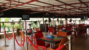 Ein Restaurant mit roten Stühlen und Tischen, einer roten Absperrschnur und einem Bildschirm an der Wand.