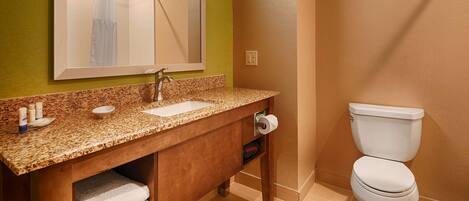 A bathroom with a granite countertop sink, a mirror, a towel rack, and a toilet.