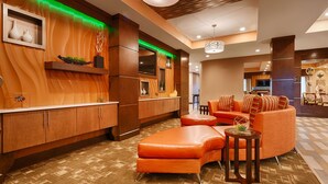 Un vestíbulo de hotel moderno con mostrador de recepción de madera, un sofá y un comedor.