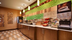 Una barra de desayuno con una cafetera, un refrigerador y diversas opciones de alimentos.