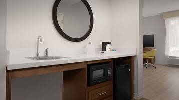 A compact kitchenette with a sink, microwave, and coffee maker.