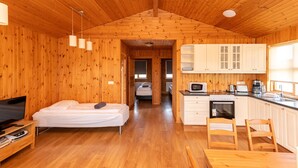 Una cabaña de madera con un dormitorio, kitchenette y un baño.