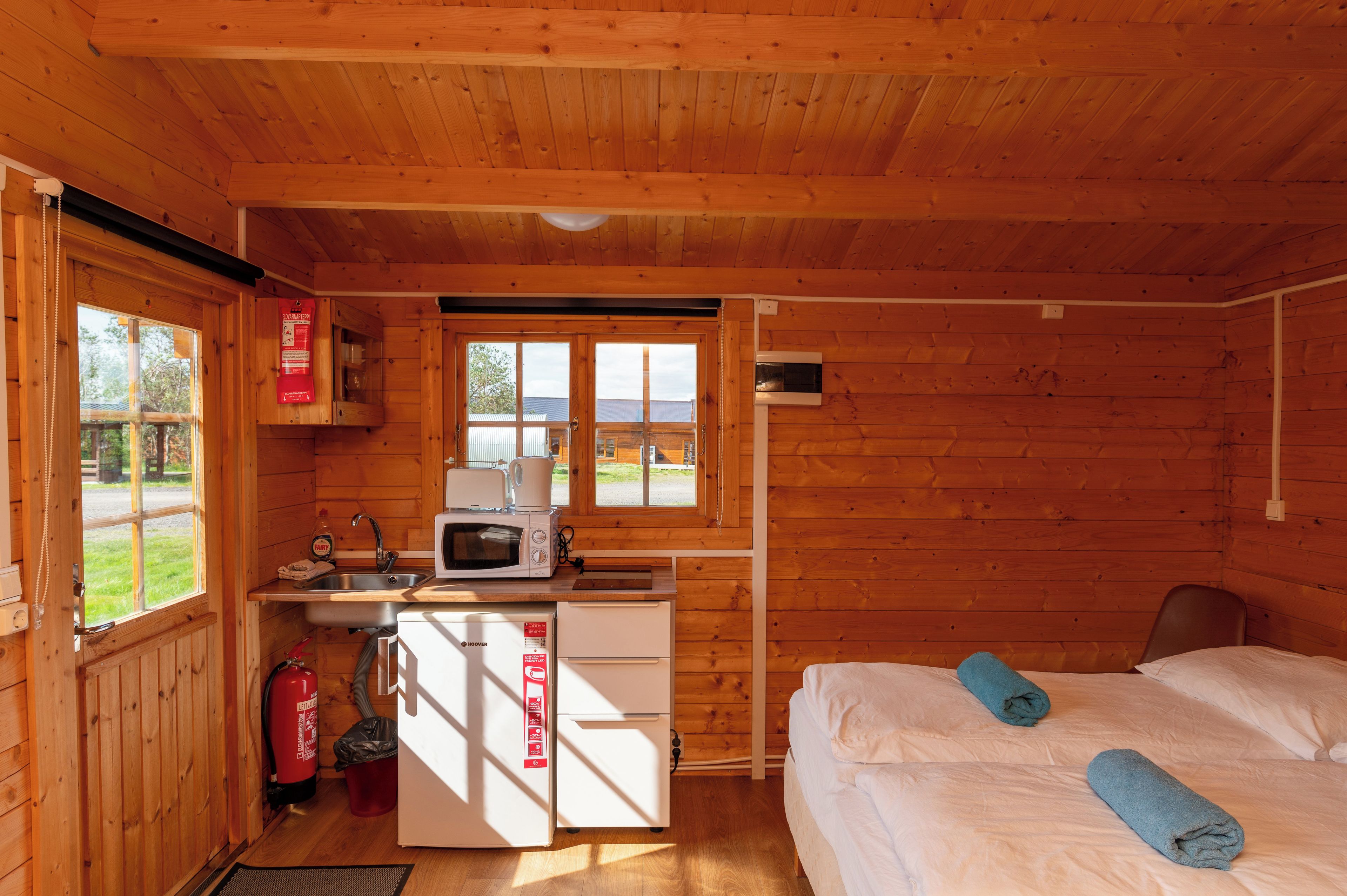 Una cabaña acogedora con kitchenette, cama y toallas, y vistas al exterior.