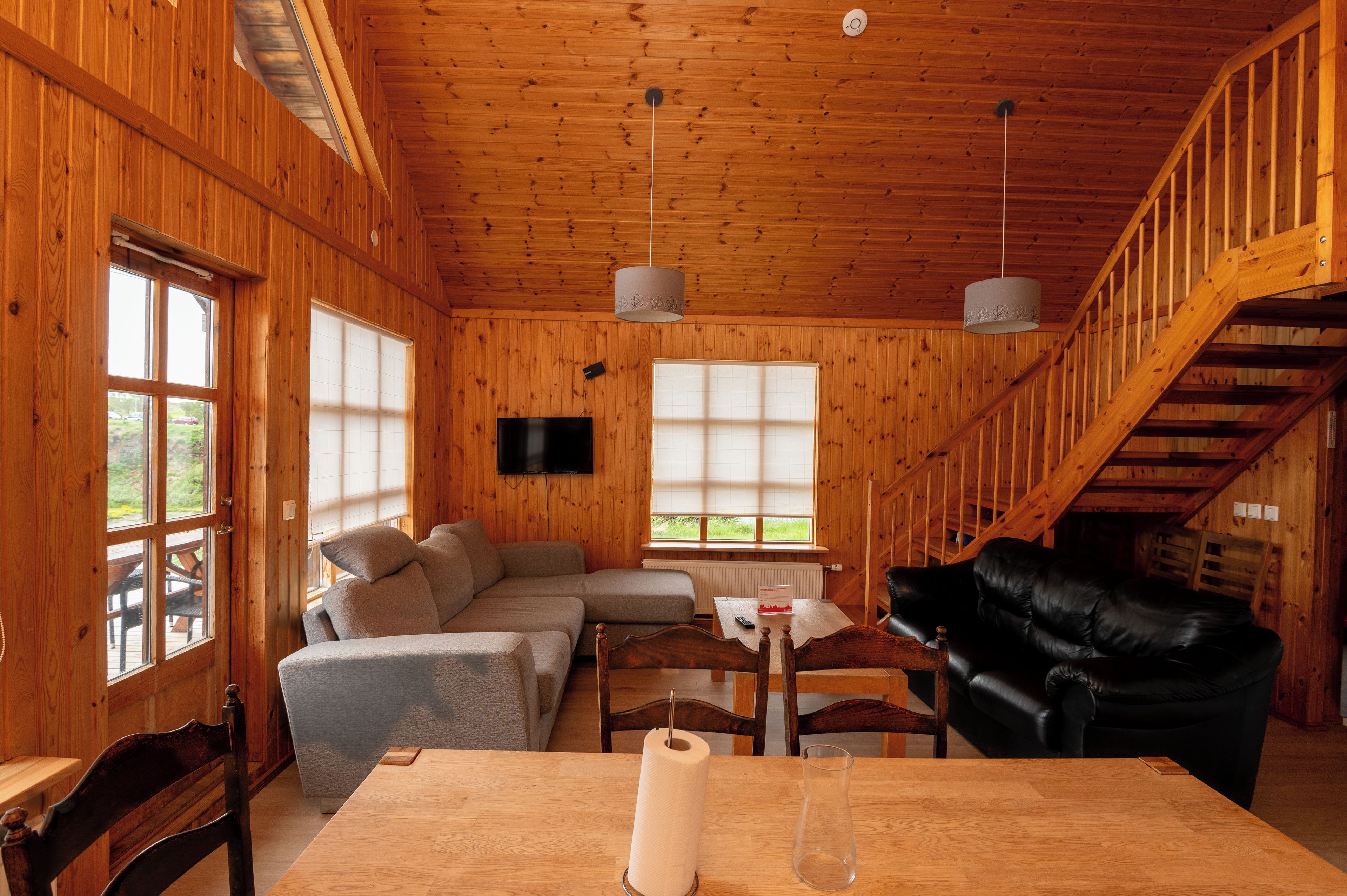 A wooden interior with a sofa, a table, and a black leather couch.