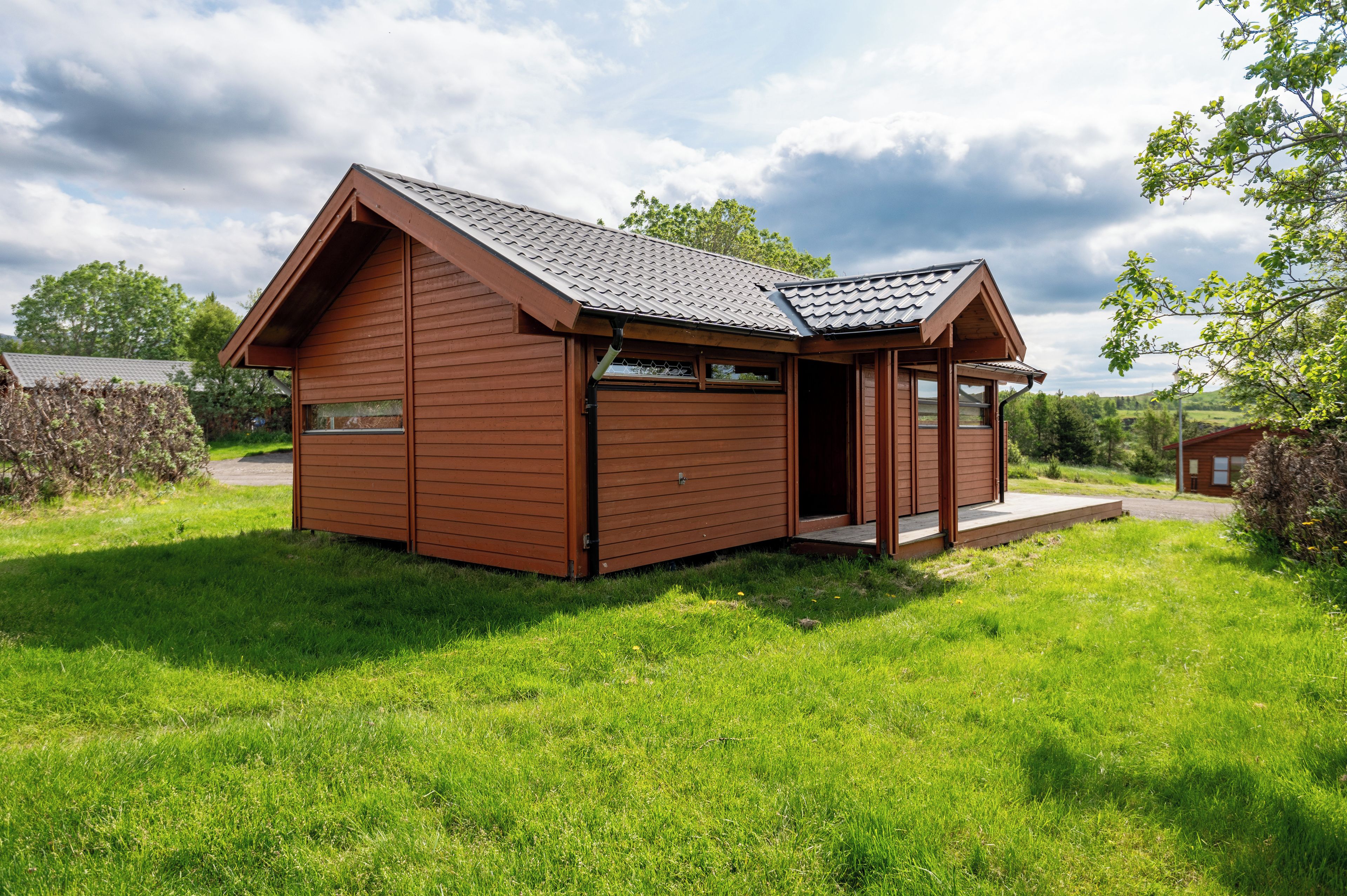 A small wooden cabin with a pitched roof, a porch, and a window.