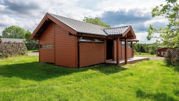 A small wooden cabin with a pitched roof, a porch, and a window.