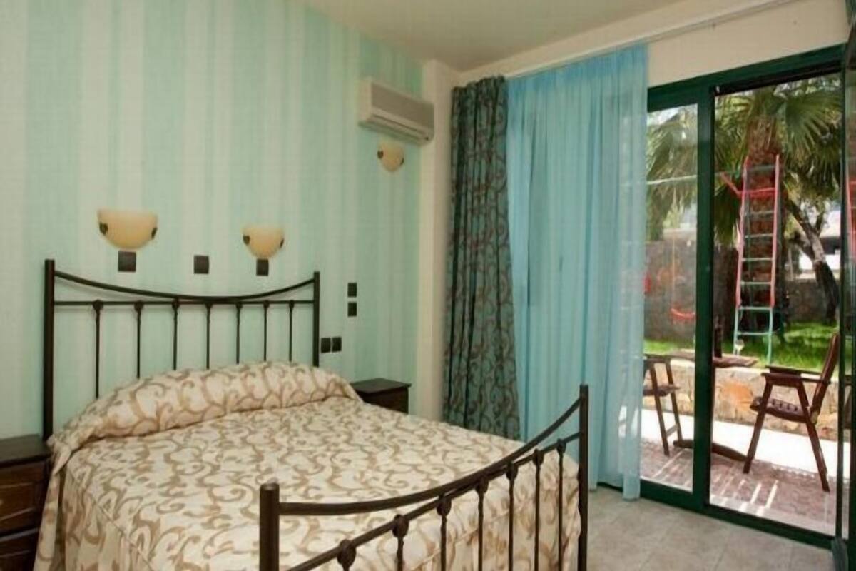 Une chambre à coucher avec un lit, une fenêtre avec des rideaux et une vue sur l’extérieur.