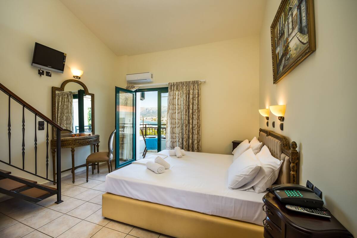Une chambre d’hôtel avec un lit, un bureau, une chaise, une télévision et un balcon.