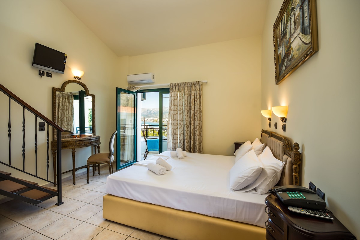 Een hotelkamer met een bed, een bureau, een stoel, een televisie en een balkon.
