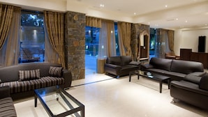 A spacious living room with a stone accent wall, leather sofas, and a glass coffee table. - Dias Luxury Studios & Apartments (Hersonissos)