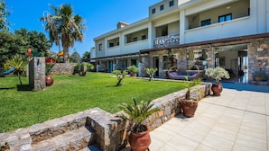 A hotel with a modern design, featuring a stone facade, a well-maintained lawn, and a clear blue sky. - Dias Luxury Studios & Apartments (Hersonissos)