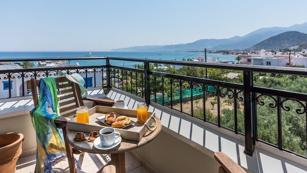 A balcony with a table set for breakfast, overlooking a coastal town and the sea. - Dias Luxury Studios & Apartments (Hersonissos)