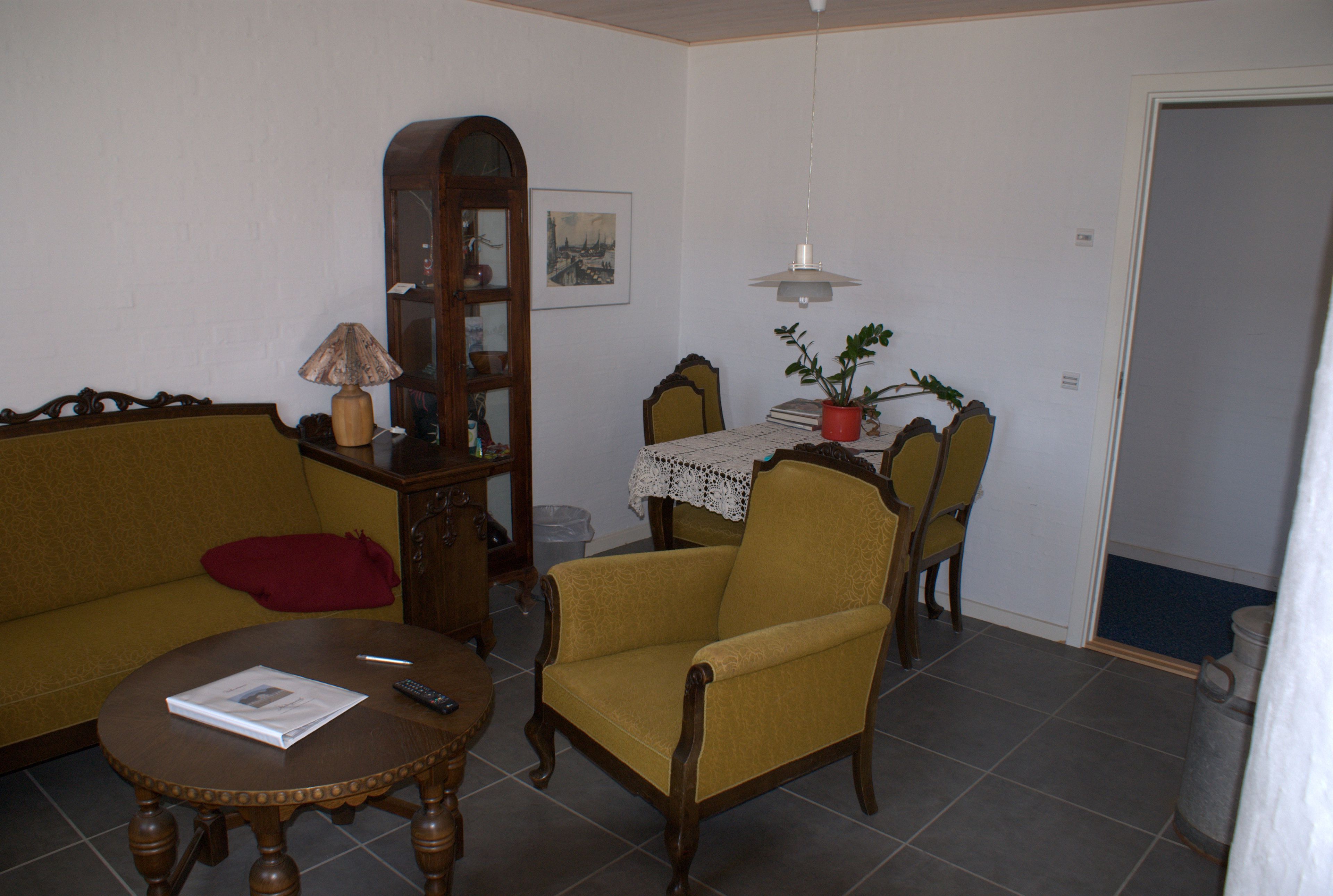 Una sala de estar con sofá, sillón, mesa de centro y una mesa de comedor con sillas.