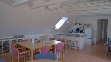 A spacious kitchen with a dining area, wooden beams on the ceiling, and a skylight.