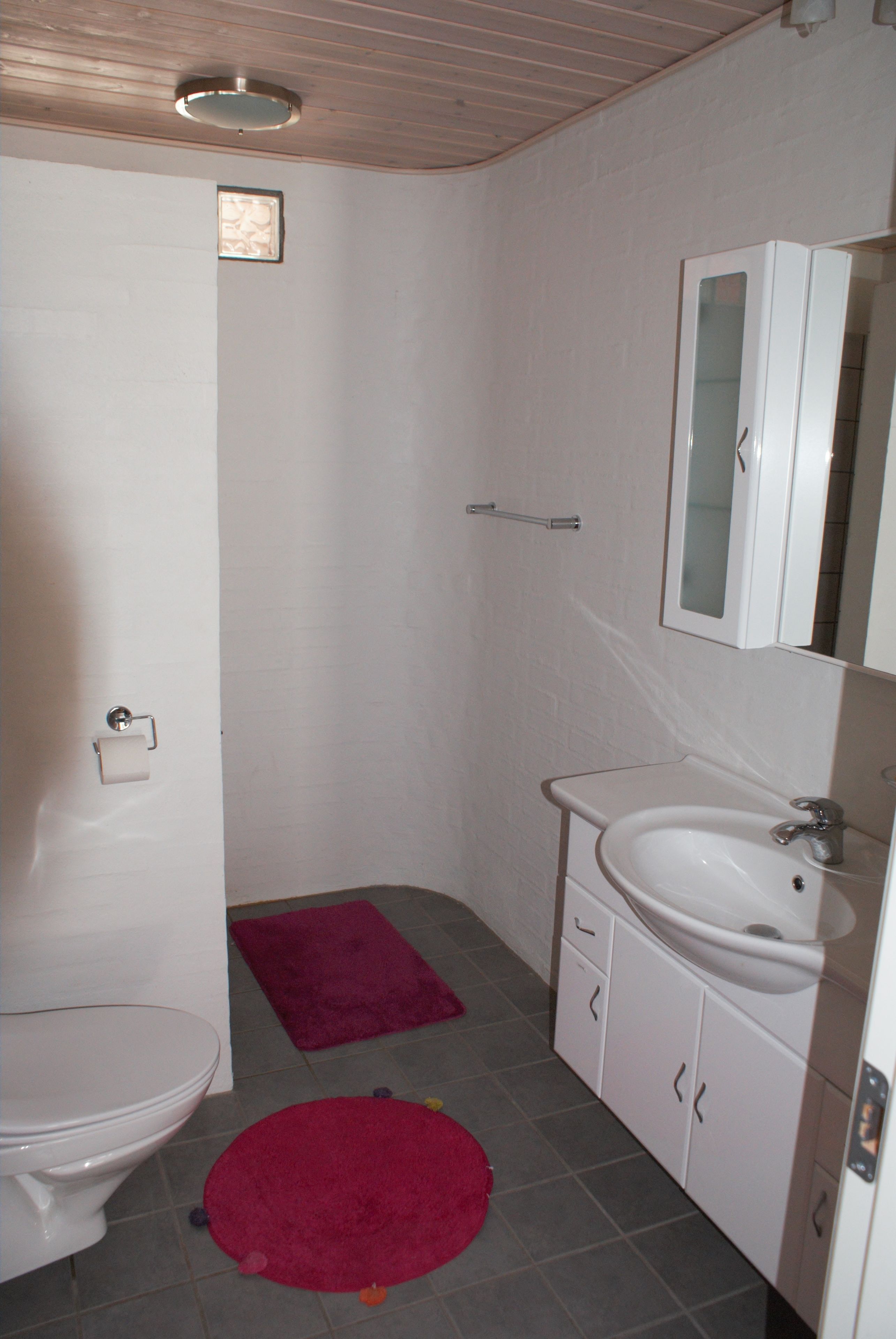 A bathroom with a toilet, sink, and mirror.