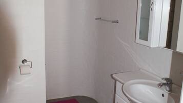A bathroom with a toilet, sink, and mirror.