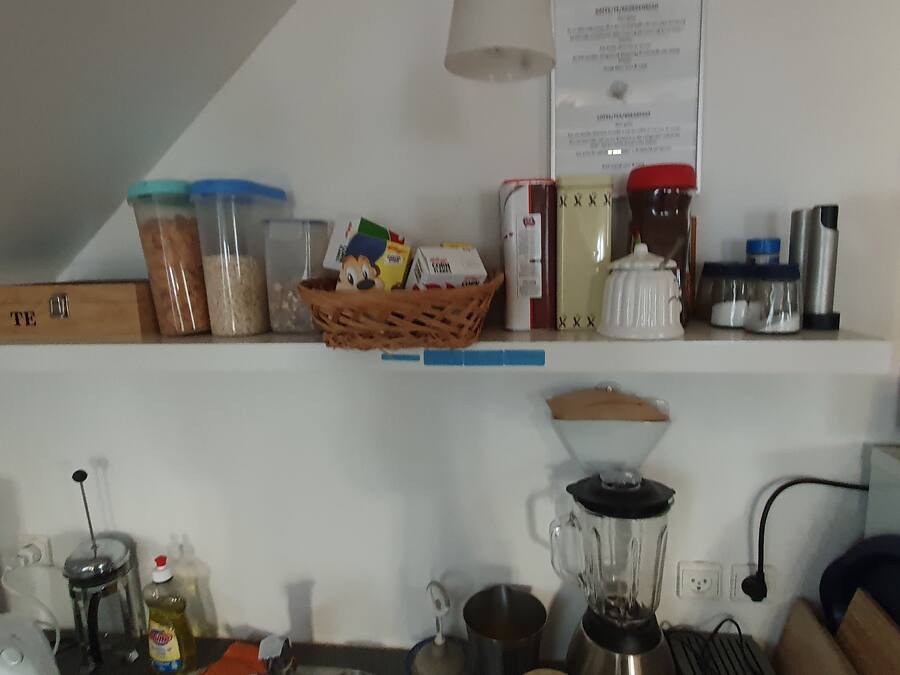 Una encimera de cocina con diversos utensilios, incluyendo frascos, una licuadora y una cesta con alimentos.