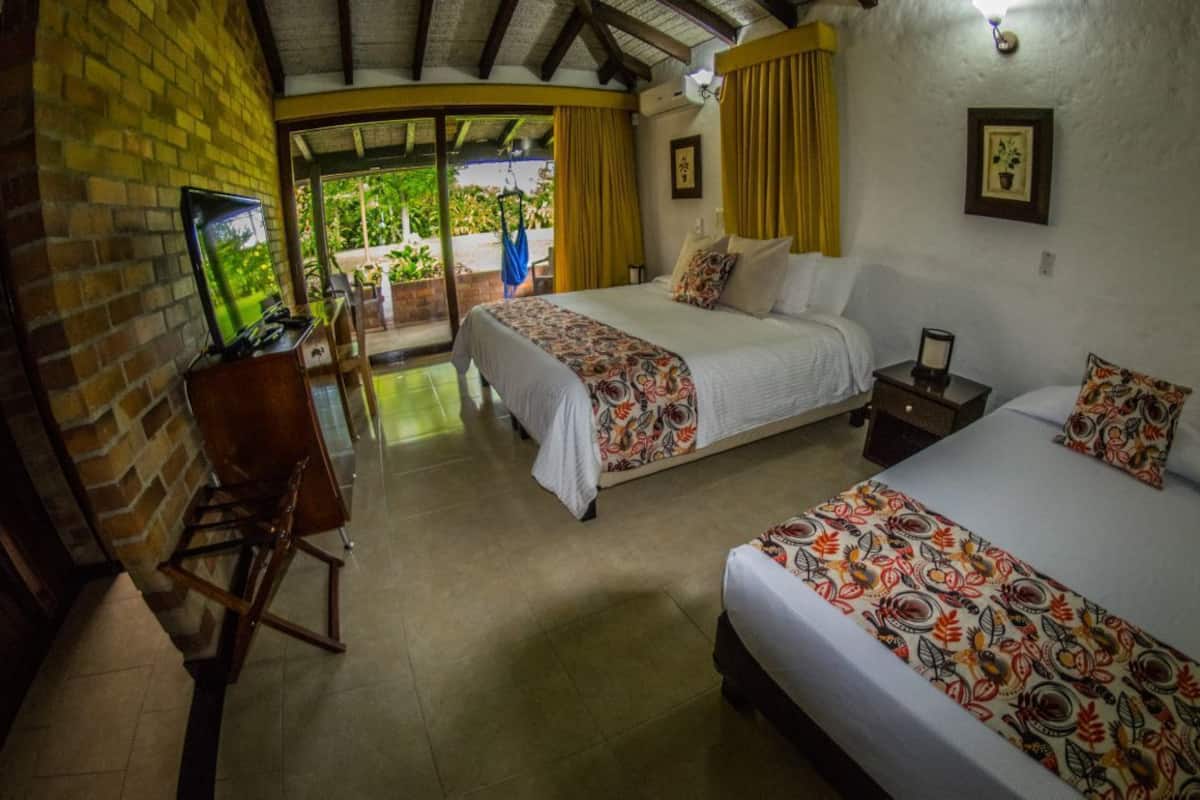 A hotel room with two beds, a TV, and a desk.