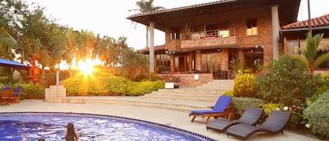 Een buitenzwembad, parasols bij het zwembad en ligstoelen