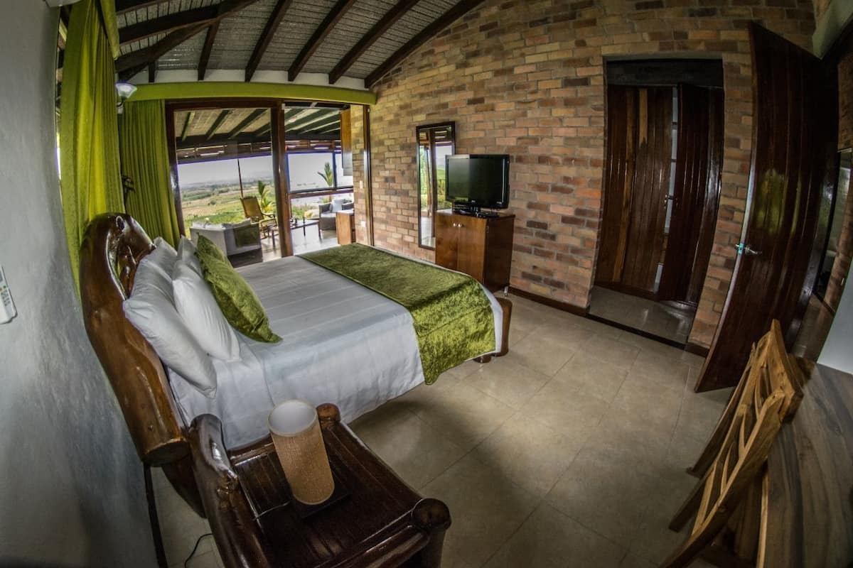 A bedroom with a bed, a television, and a view of the outdoors.