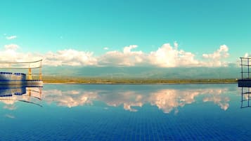 Una piscina al aire libre, sombrillas, sillones reclinables de piscina