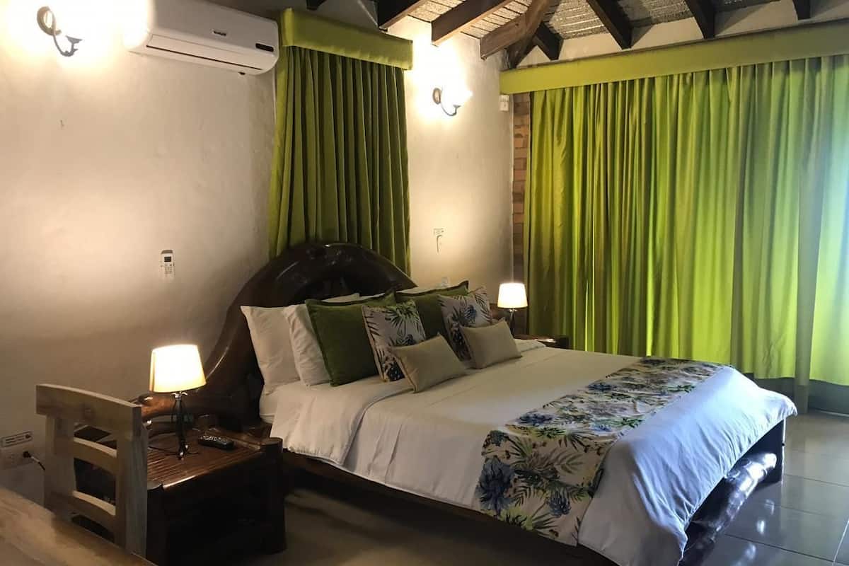 A bedroom with a bed, nightstands, and a wall-mounted air conditioner.
